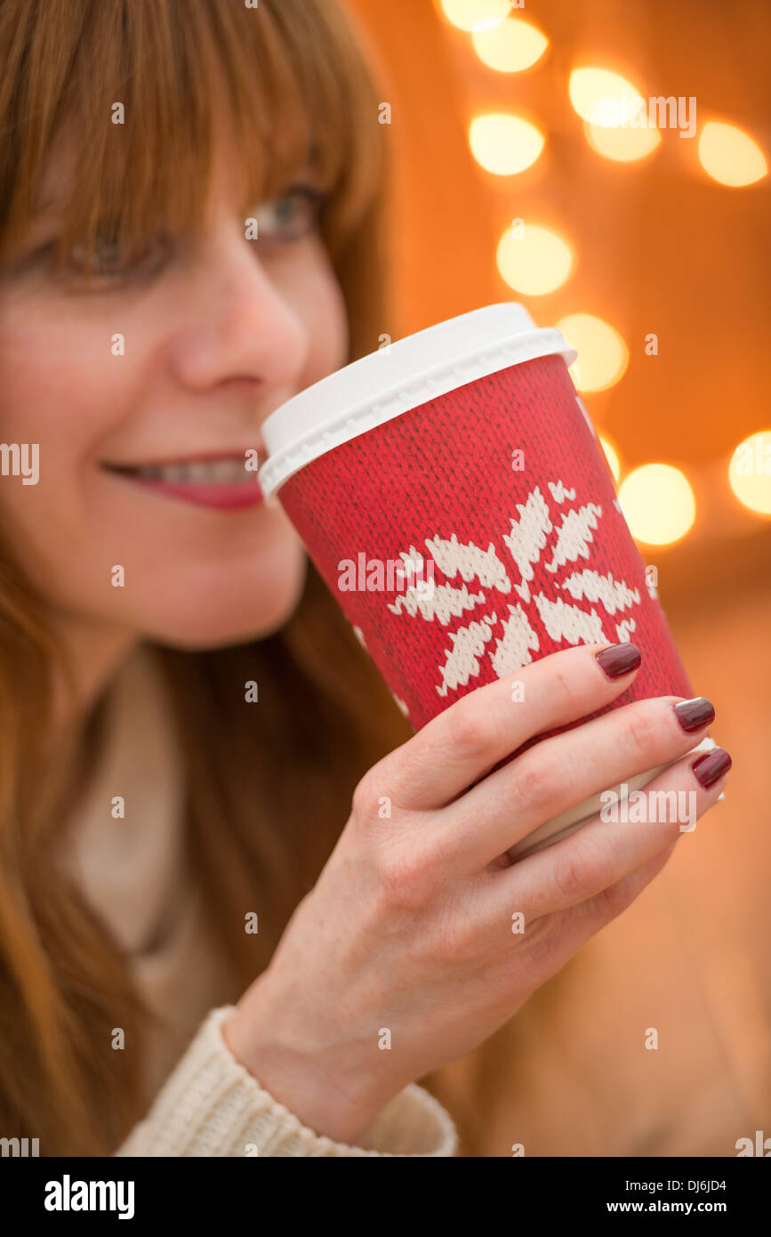 Femme buvant une boisson festive à l'époque de Noël Banque D'Images