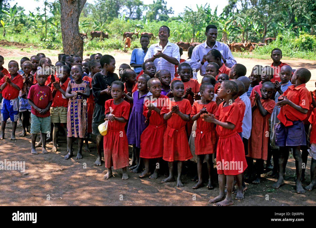 Les enfants ougandais chanter et applaudir une bienvenue aux visiteurs pour leur école Banque D'Images