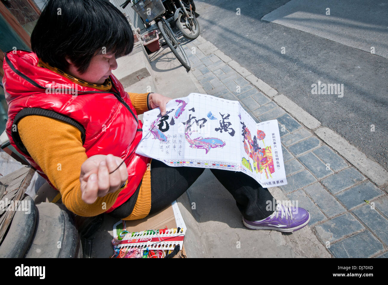 Femme faisant du point de croix dans la rue à Beijing, Chine Banque D'Images