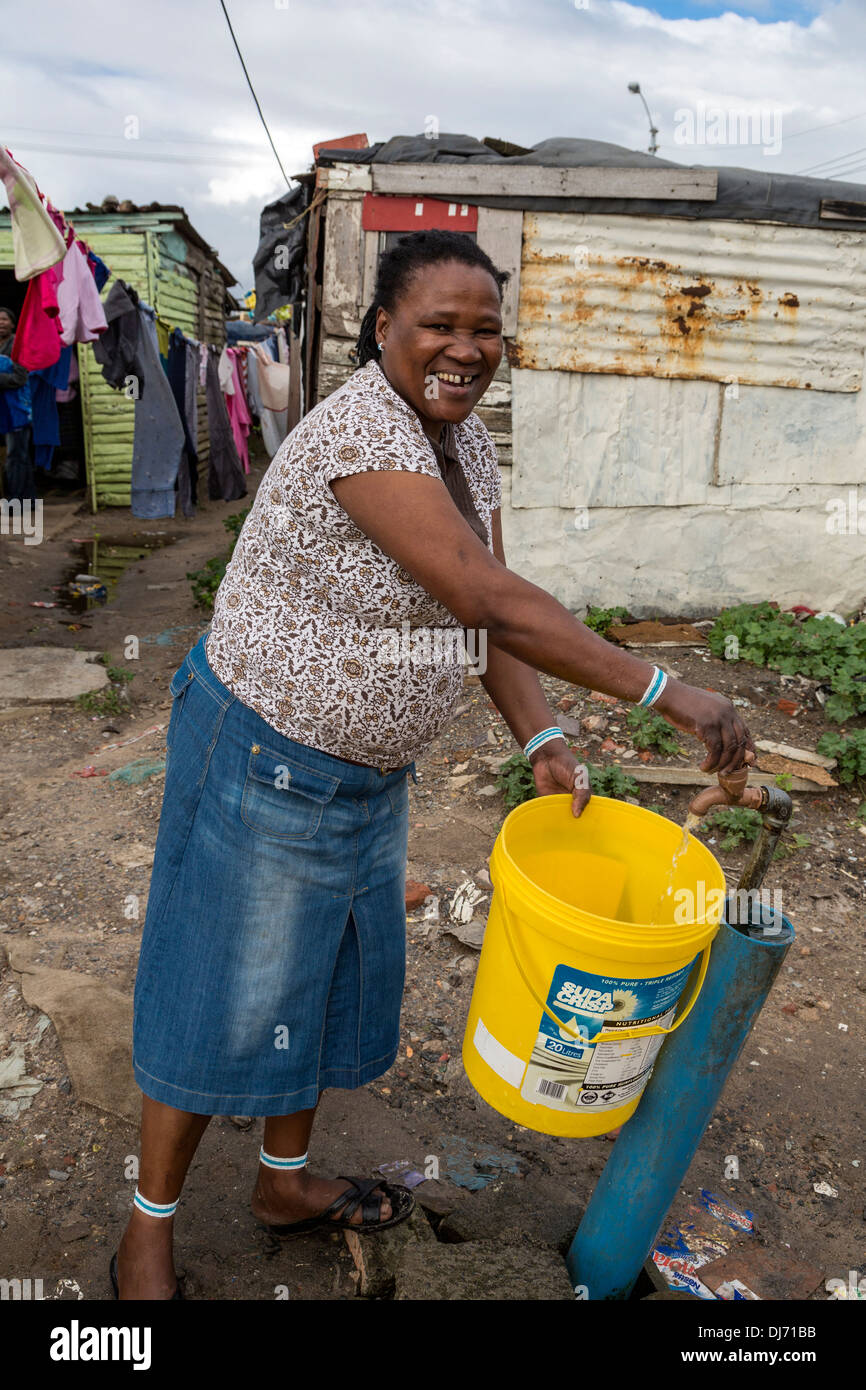 L'Afrique du Sud, Cape Town, Guguletu Township. Femme à obtenir de l'eau du robinet communal. Banque D'Images