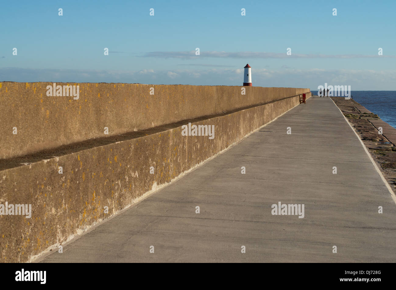 Groupe de trois personnes marchant le long de la jetée Berwick upon Tweed, Northumberland, England, UK Banque D'Images