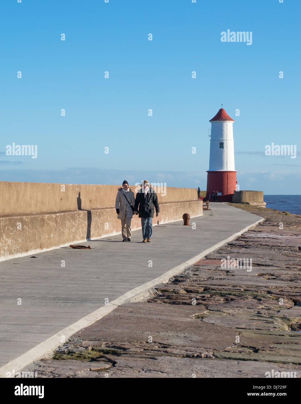 Couple marchant le long de la jetée Berwick upon Tweed, Northumberland, England, UK Banque D'Images