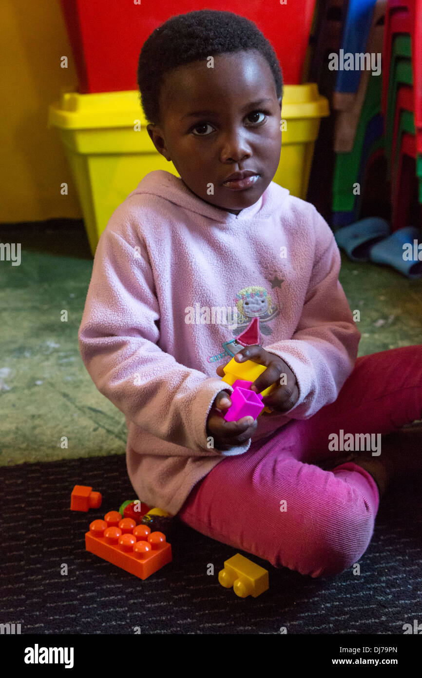 L'Afrique du Sud, Cape Town. Petit Garçon jouant avec des pièces de construction en plastique dans une garderie pour les jeunes enfants. Banque D'Images