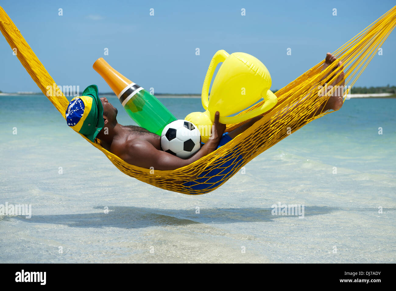 Brazilian soccer player célèbre en vous relaxant dans son hamac avec football, bouteille de champagne, et le trophée Banque D'Images