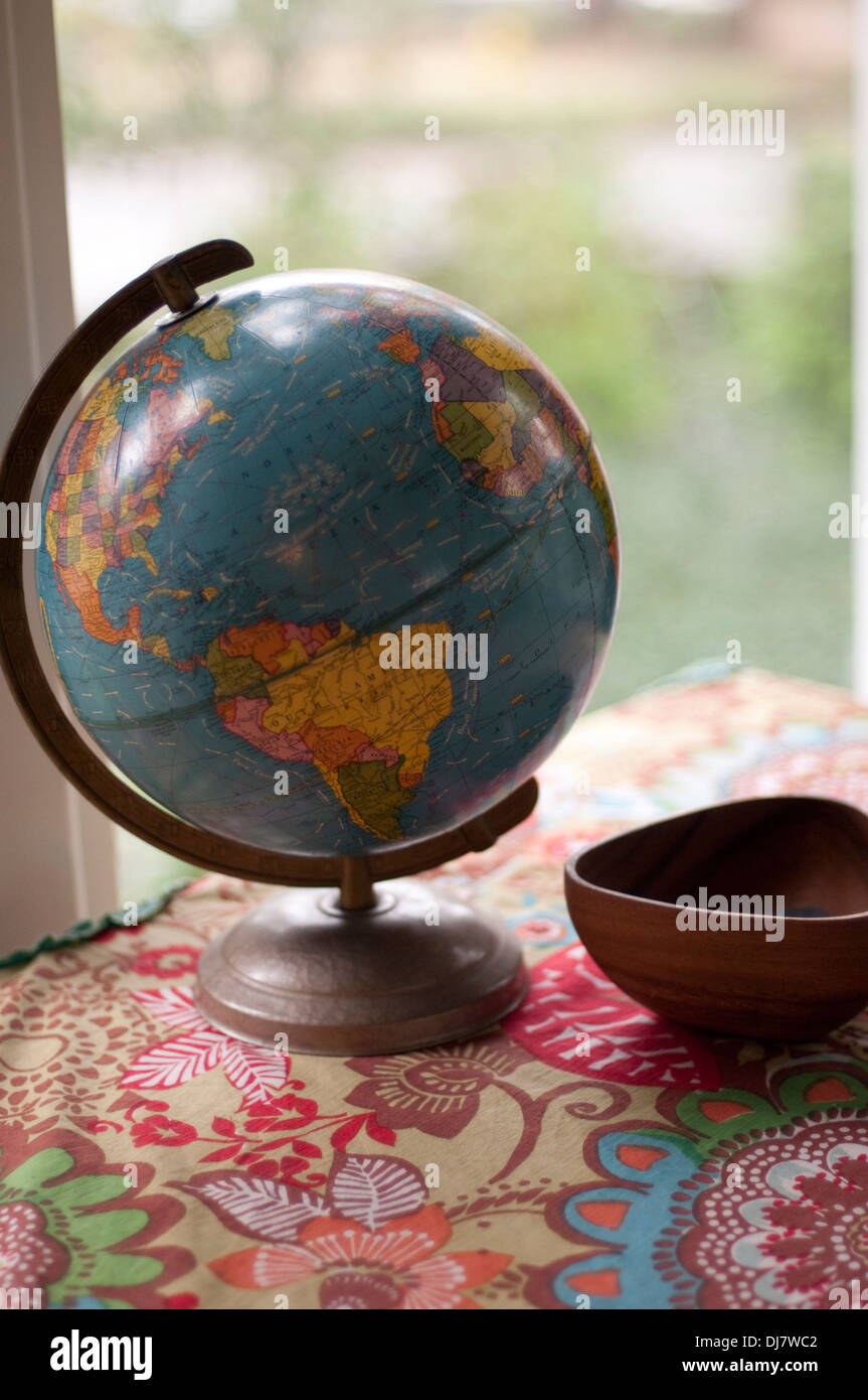 Un globe sur une nappe colorée par une fenêtre. Banque D'Images