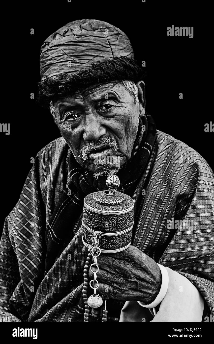 Vieux homme Budhhist bhoutanais priant isolé sur fond noir, noir et blanc Banque D'Images