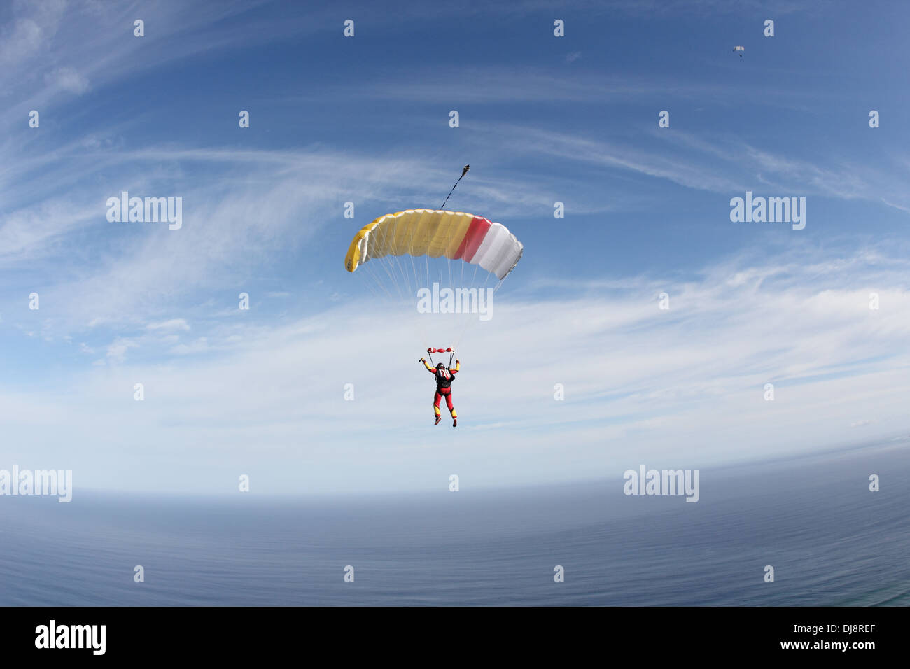 Parachutiste sous voile est voler haut dans le ciel au-dessus de nuages en direction de la mer ouverte. Elle est à la recherche d'une zone d'atterrissage appropriée ! Banque D'Images