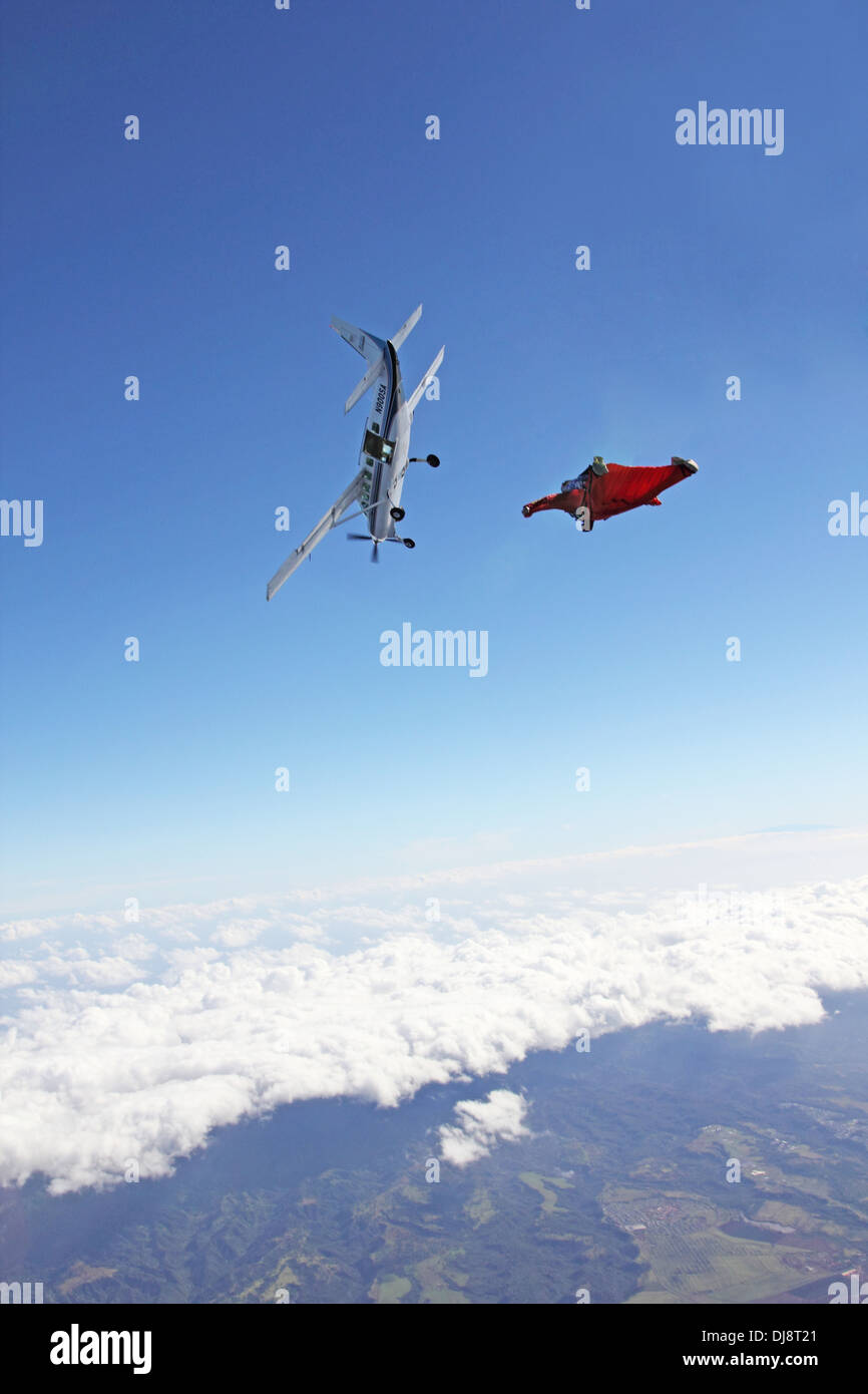 Parachutiste au sein de wingsuit spécial est de sortir d'un avion. Ce qui l'avion est la plongée et le cavalier suit vers le bas. Banque D'Images