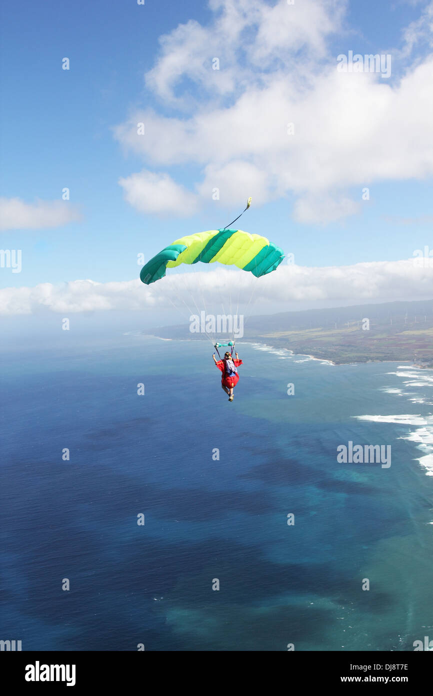 Parachutiste sous voile est survolant une ligne de rivage spectaculaire dans le ciel bleu. Banque D'Images