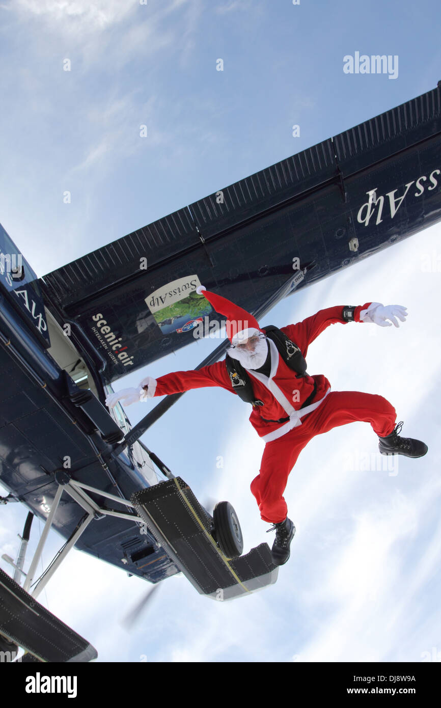 Ce parachutiste dans un costume de Père Noël saute d'un avion au cours d'une position sur le ciel bleu. Banque D'Images