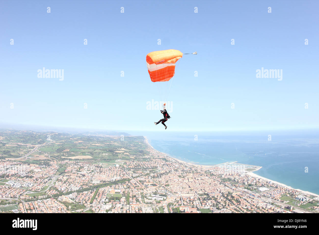 Parachutiste sous voile est de haut vol sur une grande ville à côté de la mer. Banque D'Images