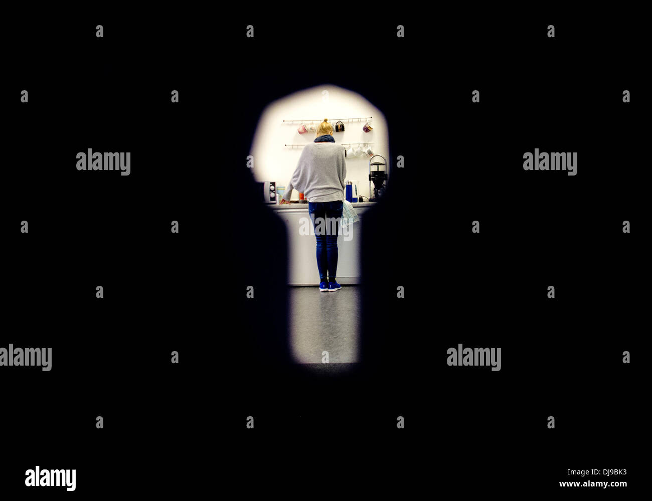 Hanovre, Allemagne. 22 nov., 2013. (ILLUSTRATION) une femme debout dans une cuisine est photographié à travers un trou de serrure à Hanovre, Allemagne, 22 novembre 2013. Après le cas d'esclavage moderne à Londres, le gouvernement britannique veut battre plus fort contre la traite des êtres humains. Trois femmes ont été censément détenues comme esclaves pendant 30 ans à Londres. Photo : Julian Stratenschulte/dpa/Alamy Live News Banque D'Images