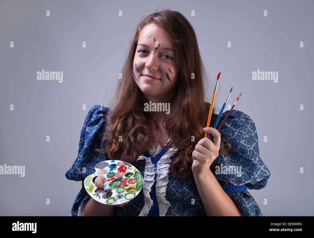 Jeune peintre rond humide avec palette et pinceaux face holding Banque D'Images