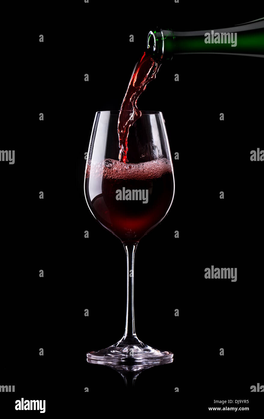 Le vin rouge est versé dans un verre sur un fond noir Banque D'Images