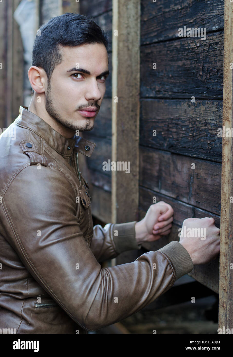 Beau jeune homme, appuyant sur les poings sur plancher bois mur et looking at camera Banque D'Images