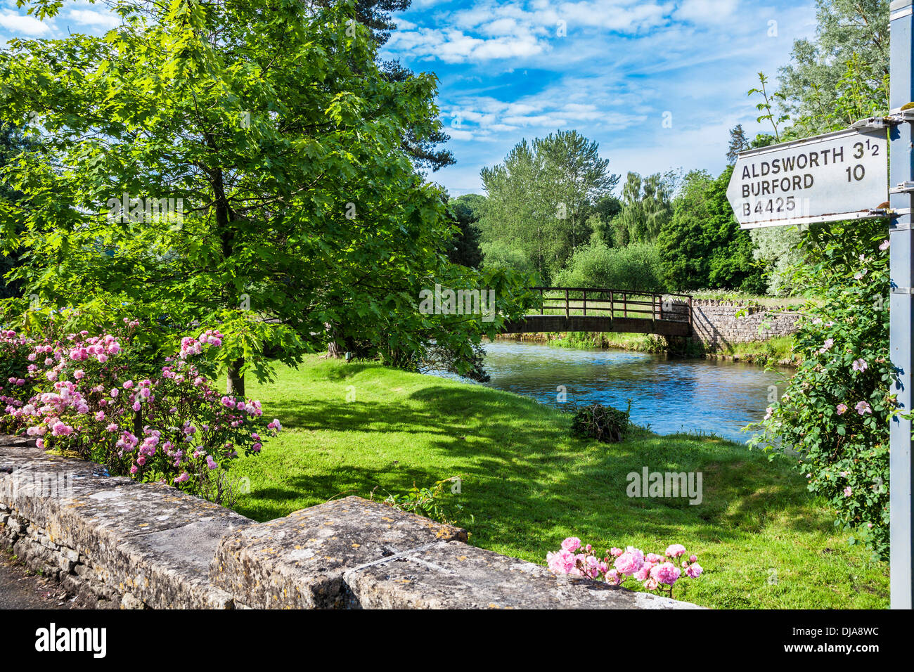 Vue sur la rivière Coln en Bibury avec un panneau routier vers d'autres villes et villages des Cotswolds et la ferme de truites. Banque D'Images