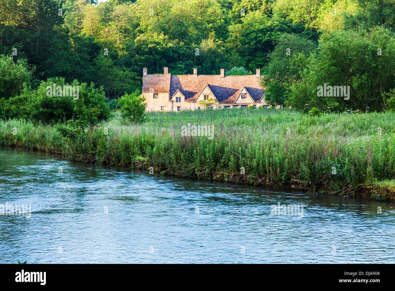 Vue sur la rivière Colne et le rack de l'eau à l'Isle prés célèbre Arlington Row chalets dans les Cotswold village de Bibury. Banque D'Images