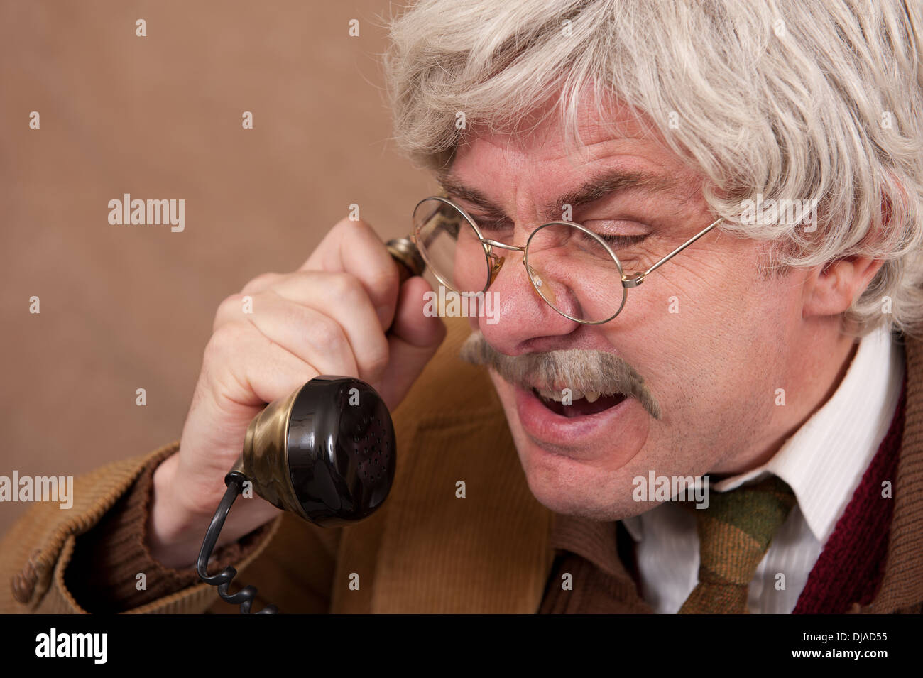 Vieil homme aux cheveux gris en colère tout en criant au téléphone. Banque D'Images