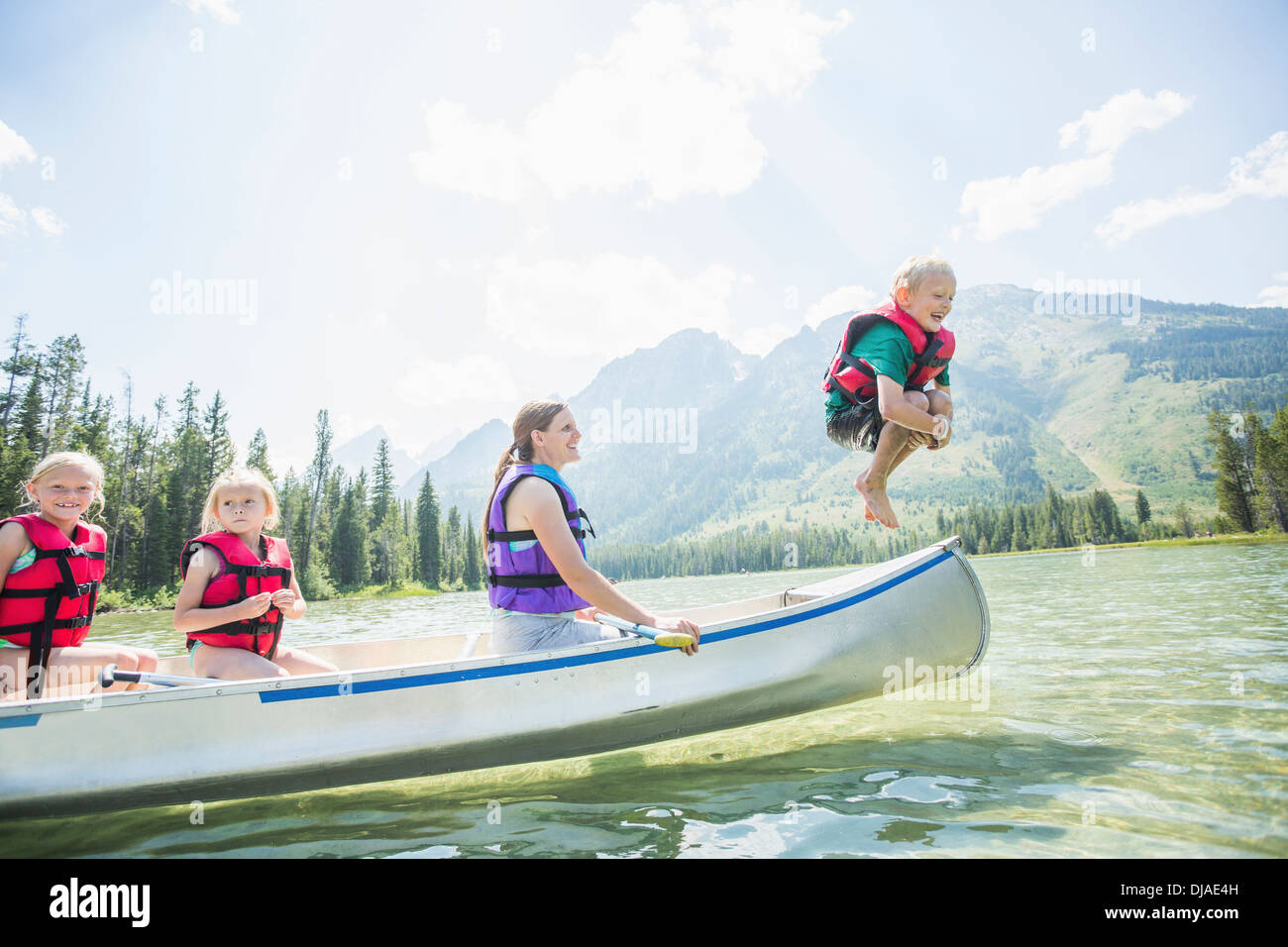 Caucasian boy jumping de canoe dans le lac Banque D'Images