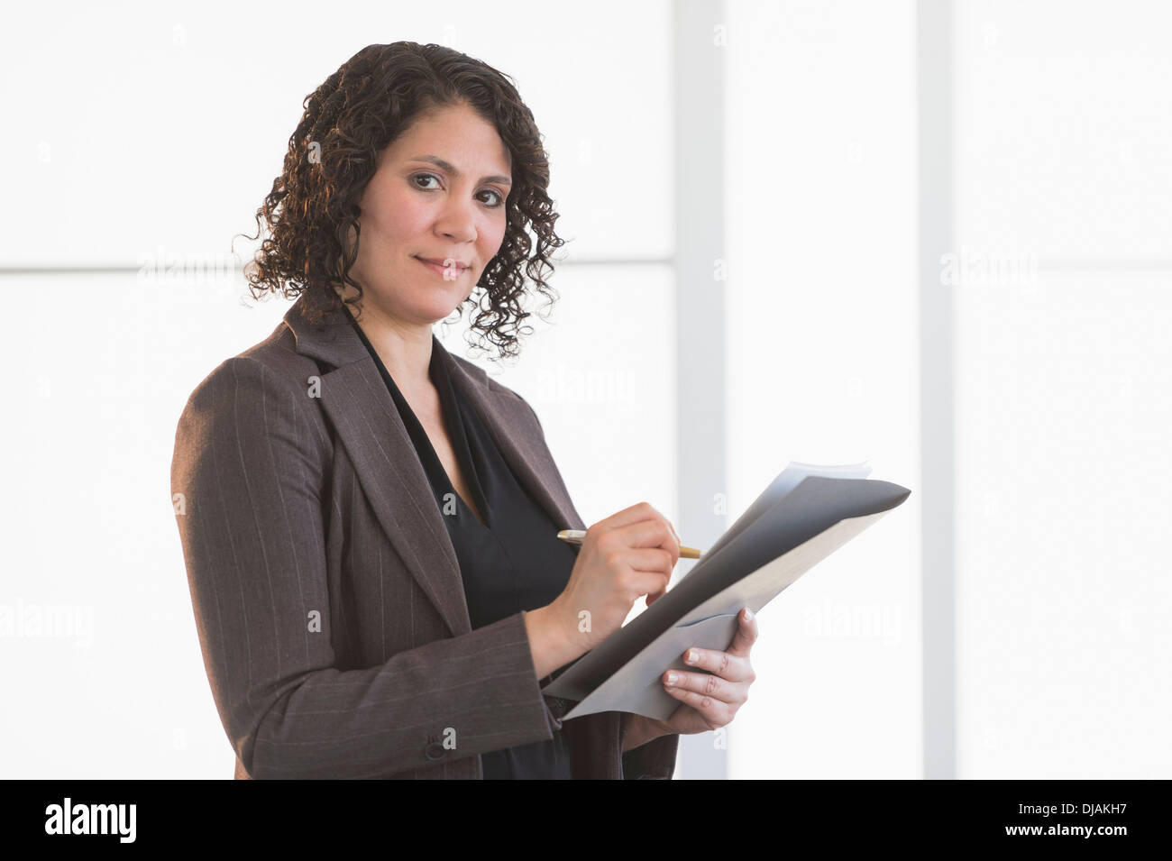 Hispanic businesswoman writing in office Banque D'Images