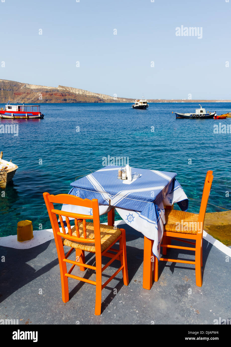 Table et chaises en face de la mer avec mer bleue et le ciel comme arrière-plan dans Ammoudi, Santorin, Grecee Banque D'Images