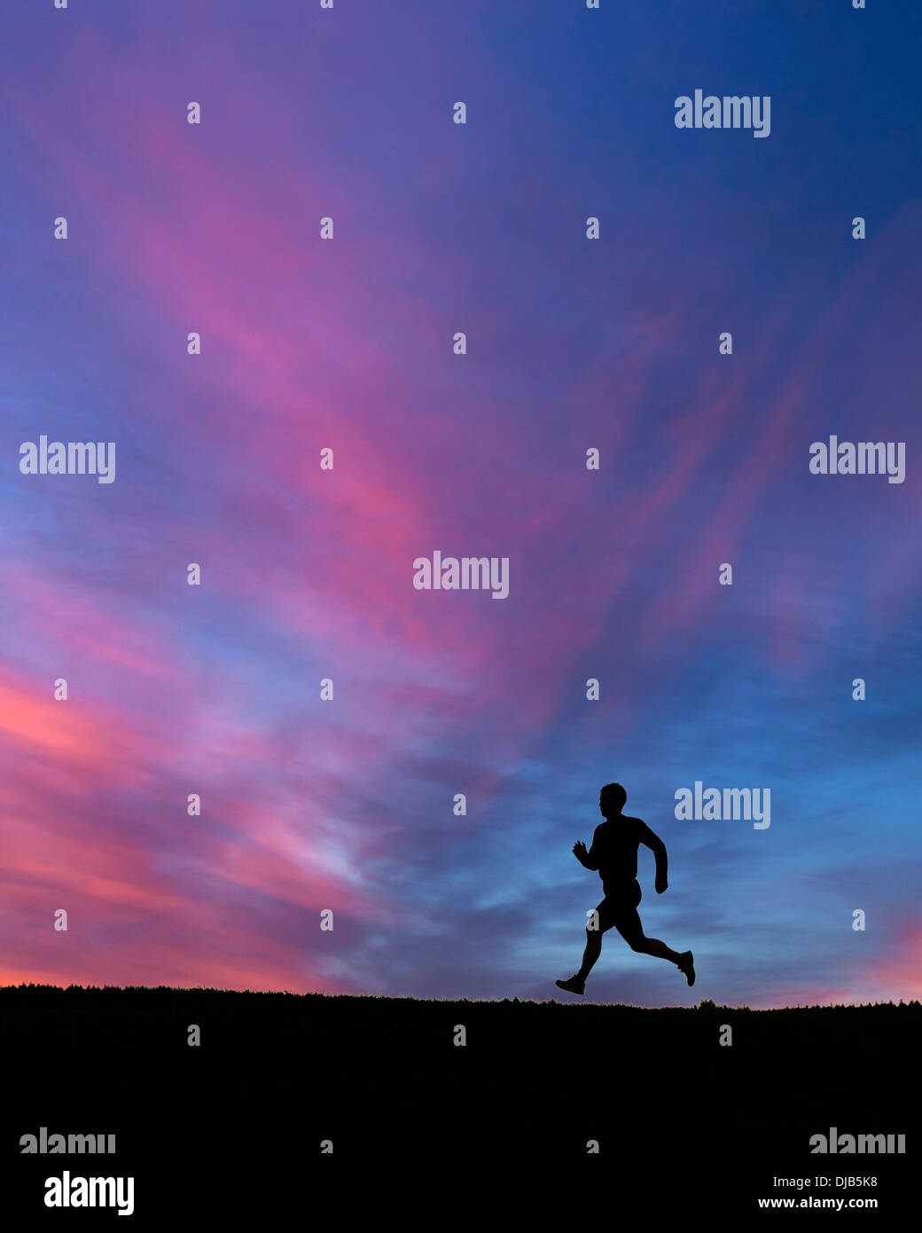 Silhouette d'un jogger au coucher du soleil Banque D'Images