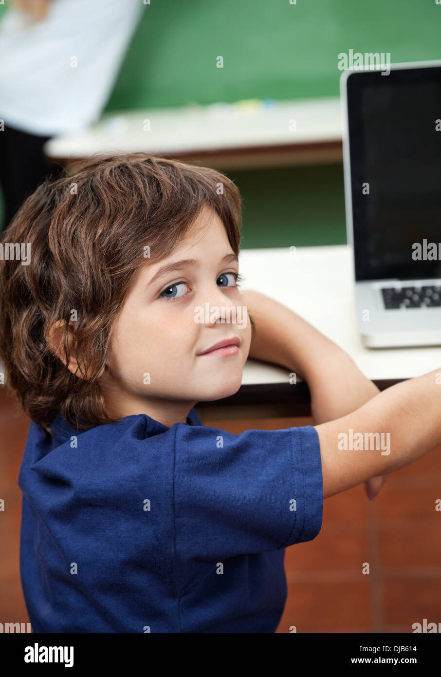 Boy With Laptop On Desk In Classroom Banque D'Images