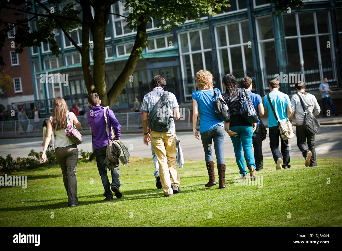 Retour tourné de grand groupe d'étudiants de l'université de marcher à travers le campus de l'herbe en plein soleil Banque D'Images
