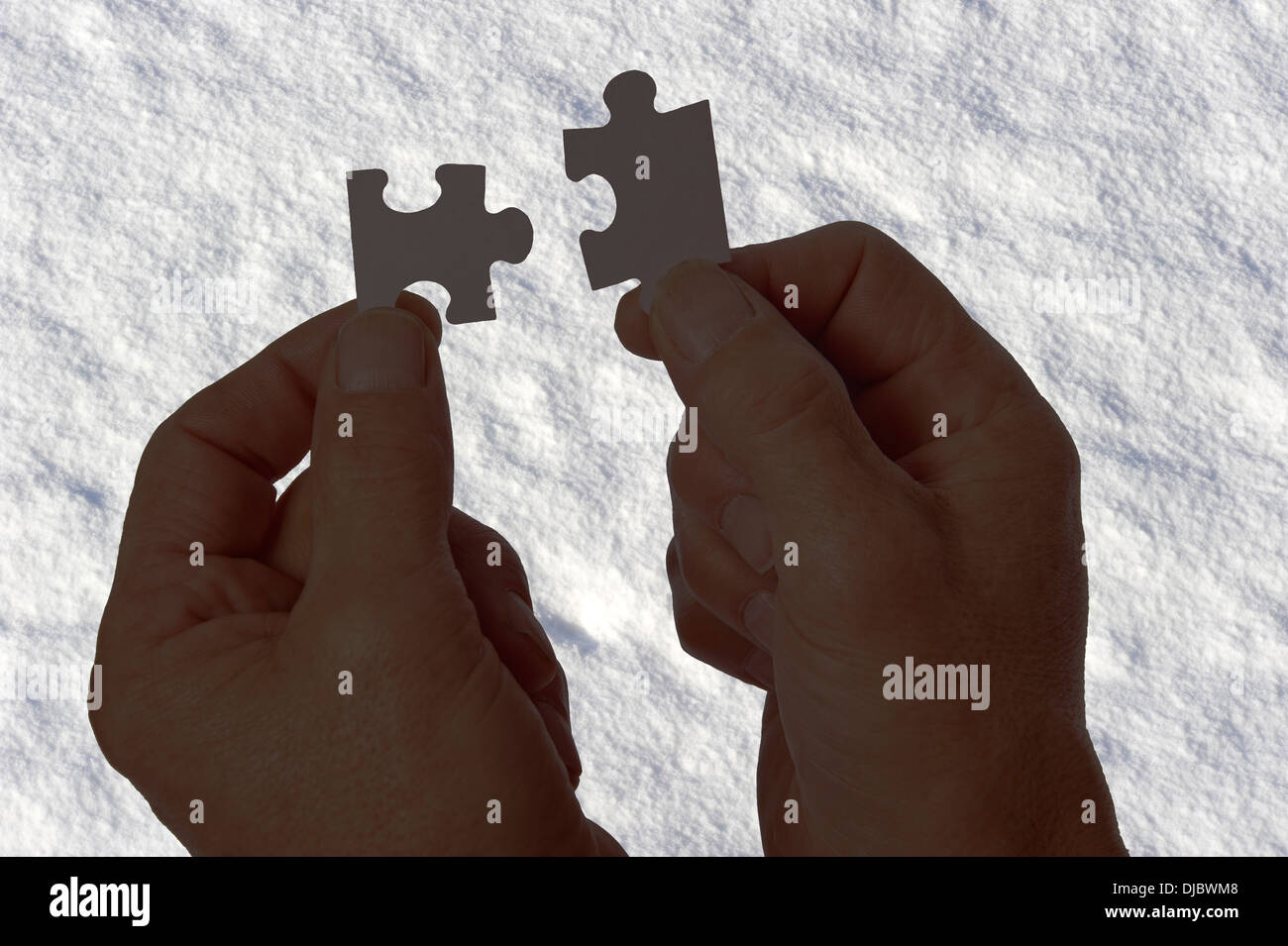 Deux mains en silhouette contre l'arrière-plan blanc neige connecter jigsaw puzzle pieces Banque D'Images