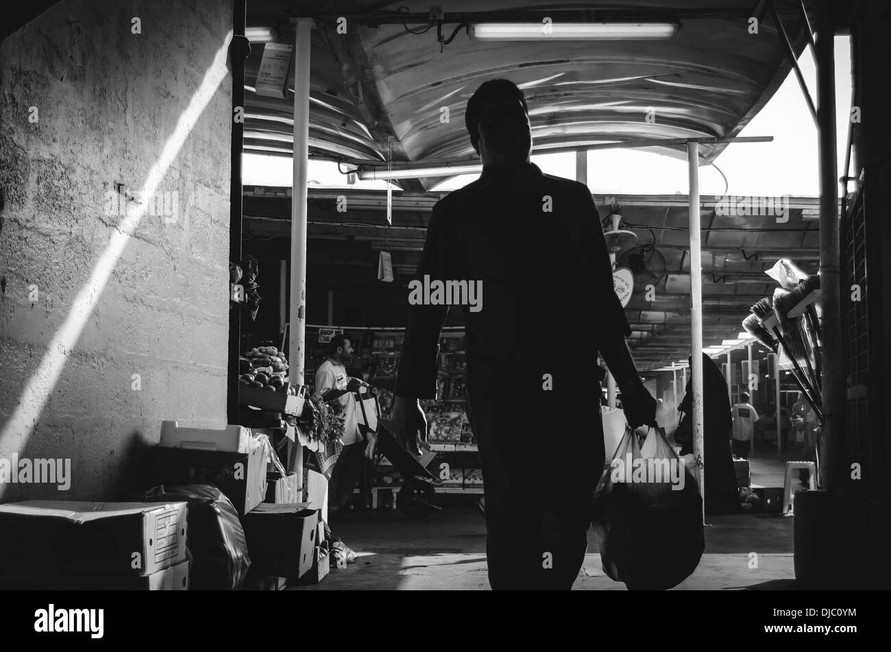 Homme tenant un sac shopping en marchant dans une ruelle sombre à l'intérieur du Deira Marché de Fruits et légumes. Dubaï, Émirats arabes unis. Banque D'Images