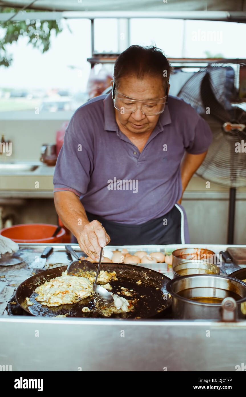 Un Hawker center cuire la préparation des huîtres Huîtres frites (omelette) à son échoppe à Gurney Drive, Penang, Malaisie Banque D'Images