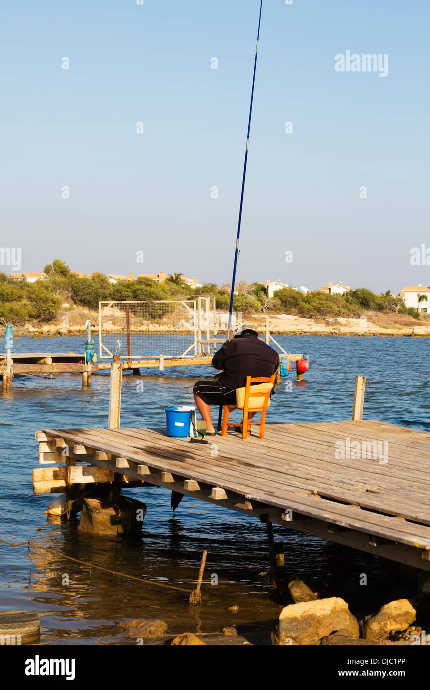 Petit pêcheur assis sur une chaise, d'une jetée de pêche au ruisseau Potamos, Liopetri Chypre Banque D'Images