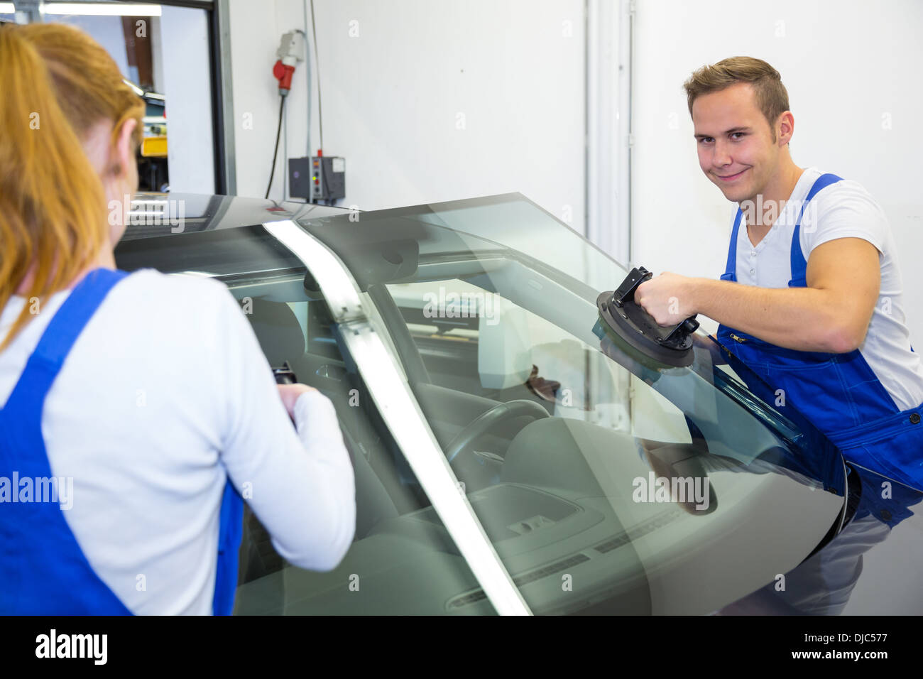 Remplacement de pare-brise pare-brise ou sur une voiture par couple de vitriers en garage Banque D'Images