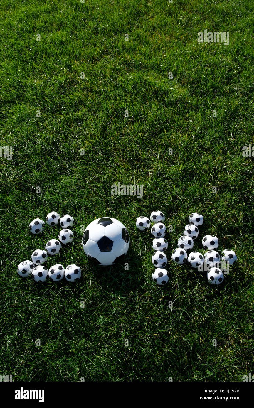 Message pour 2014 faite avec de petits ballons de football sur terrain de football en herbe verte Banque D'Images
