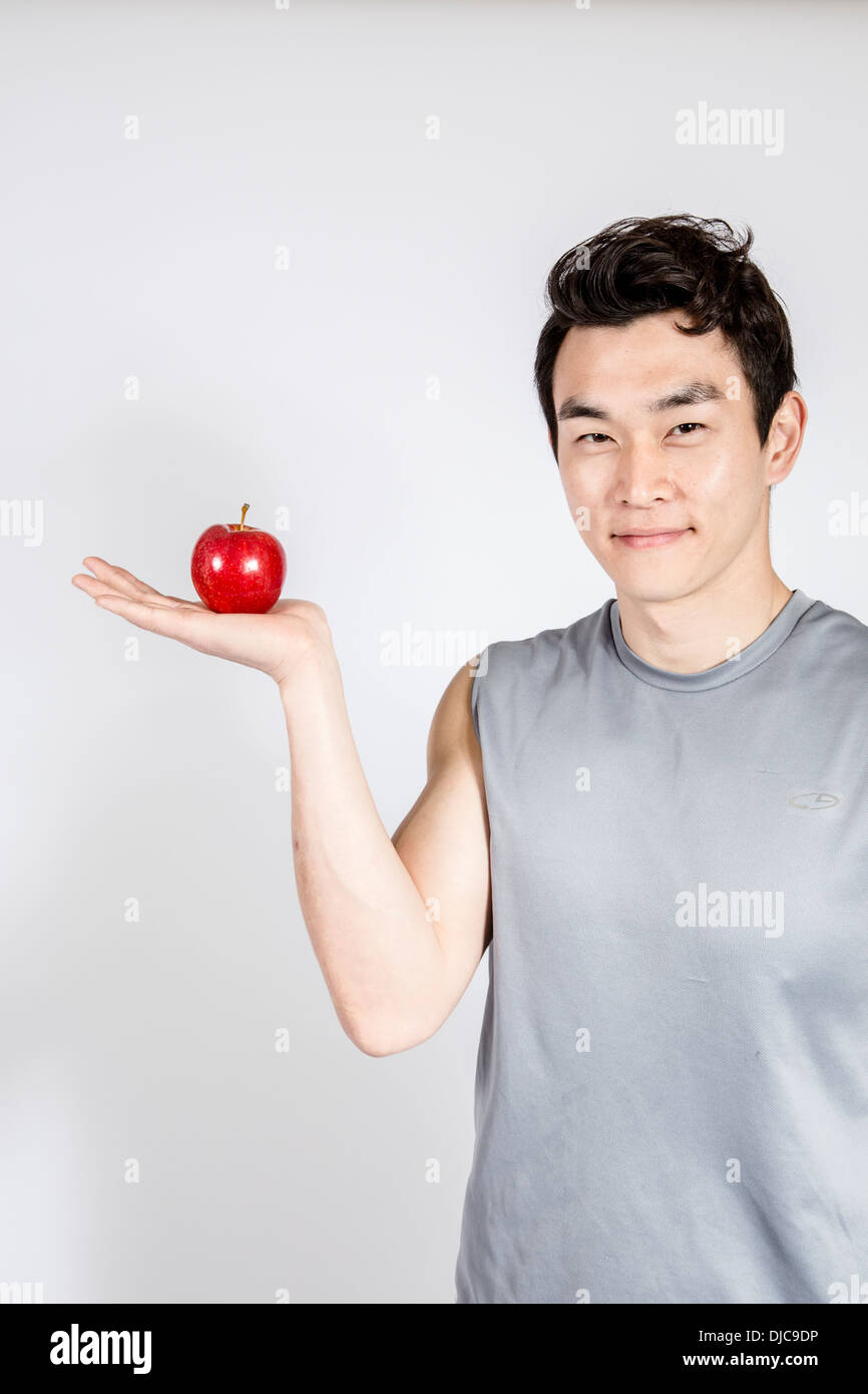Smiling young man holding red apple à Palm Banque D'Images