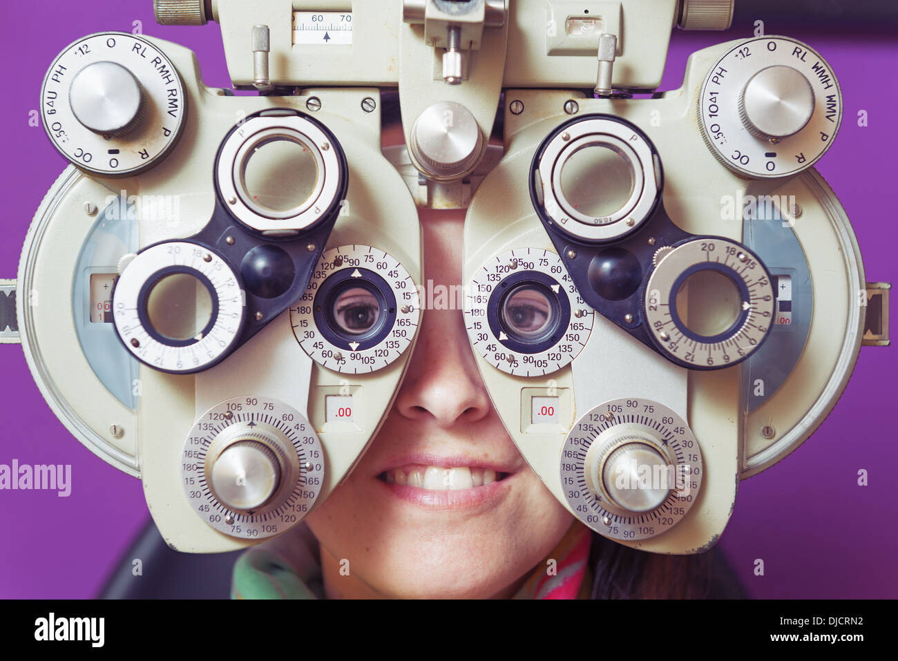 Une femme assise derrière l'Optométrie l'équipement dans l'examen de la vue ; Tarifa, Cadix, Andalousie, Espagne Banque D'Images