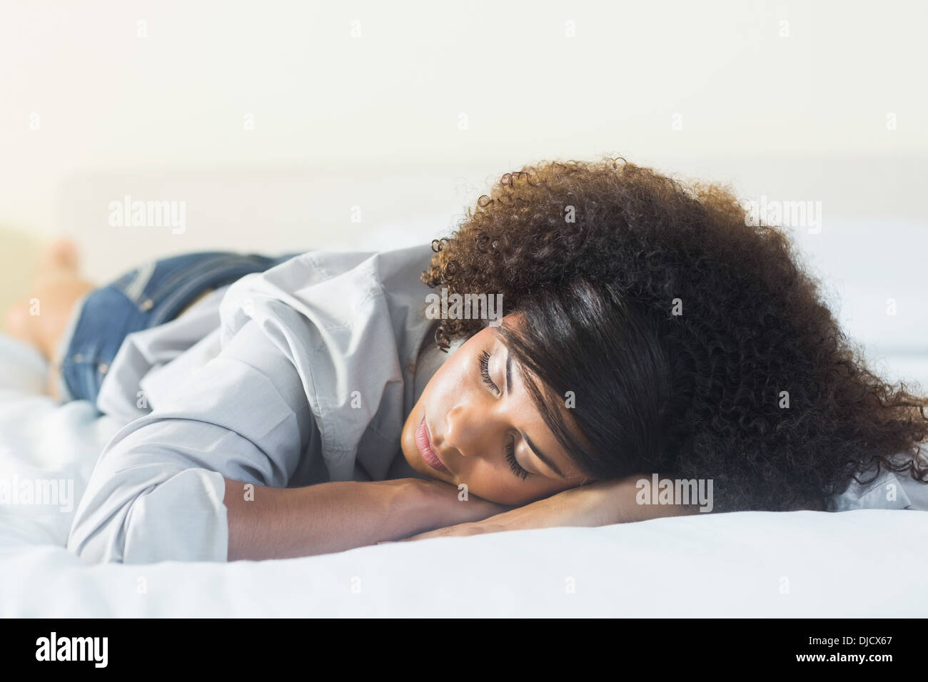 Pretty peaceful brunette lying on bed resting head on hand Banque D'Images