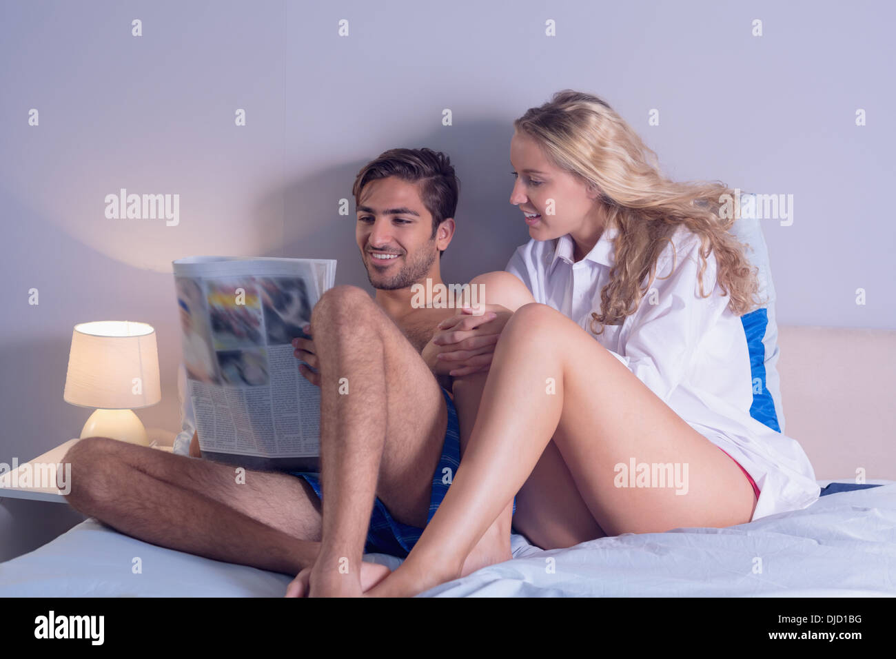Beau couple assis sur leurs bed reading newspaper Banque D'Images