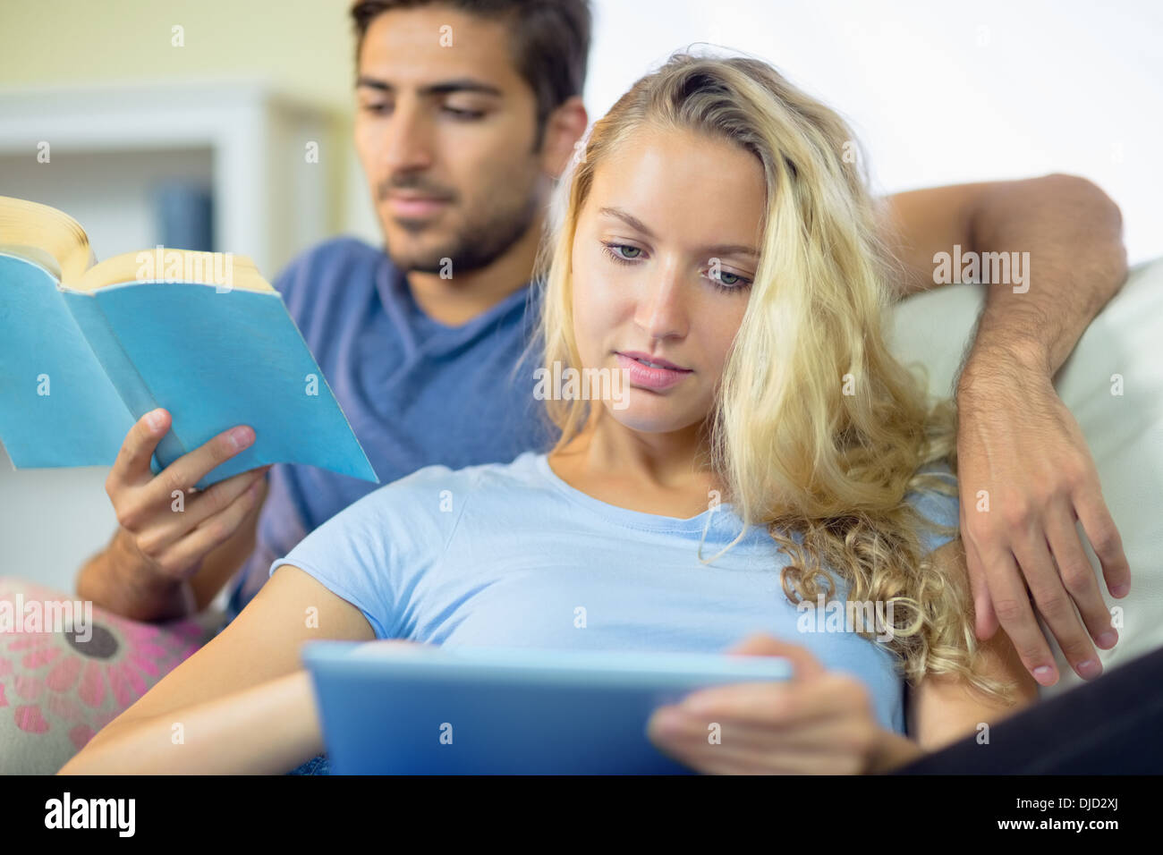 Jeune couple concentré en utilisant une tablette et de la lecture Banque D'Images