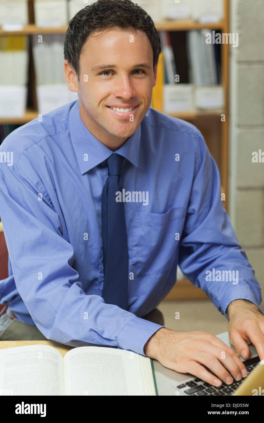 Bibliothécaire joyeux l'aide d'un ordinateur portable Banque D'Images