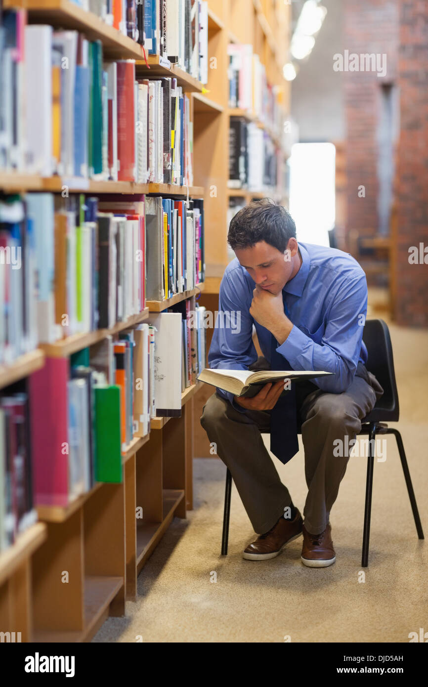 Bibliothécaire porté assis à côté d'étagère et de lecture Banque D'Images