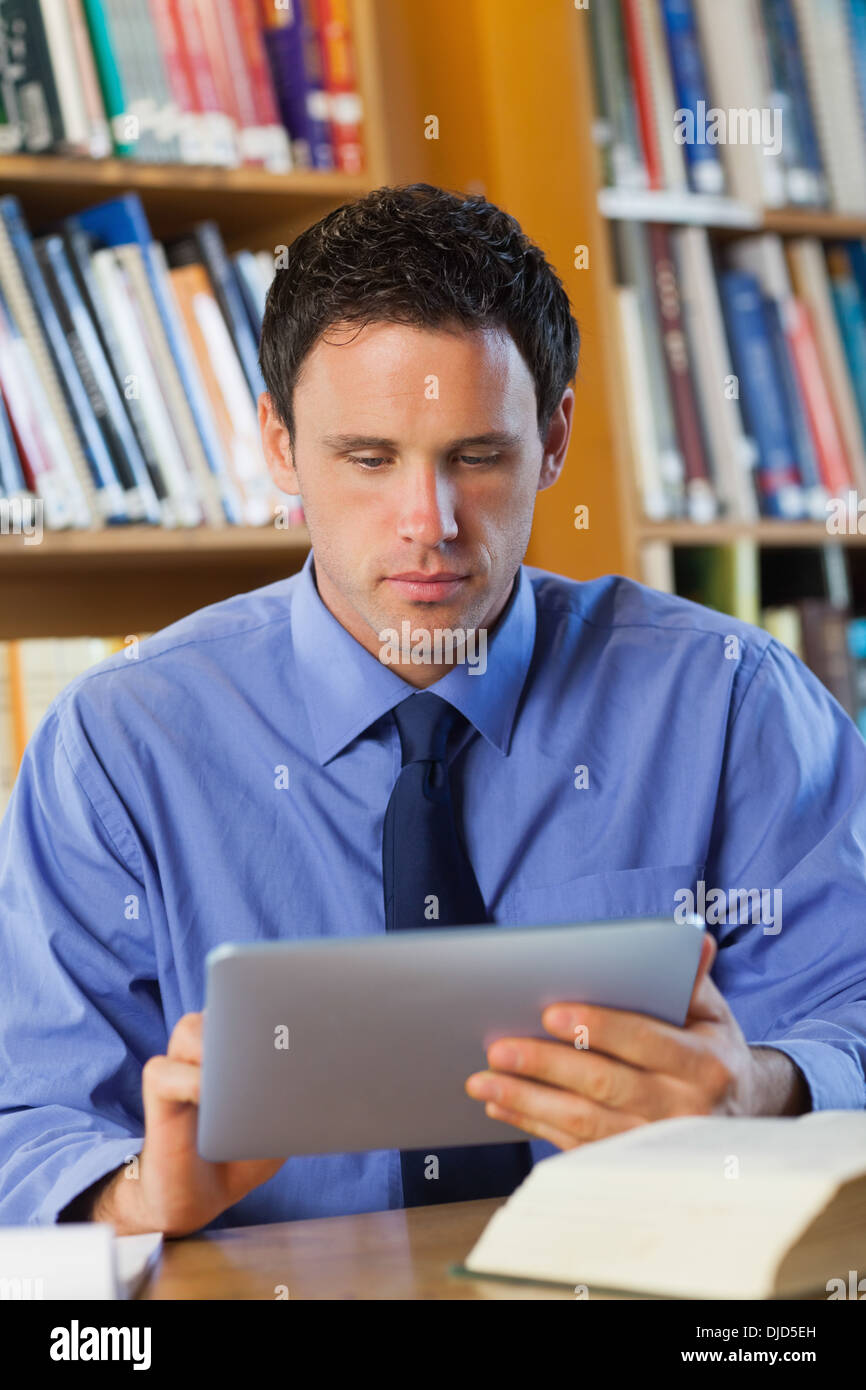 Bibliothécaire calme sitting at desk using tablet Banque D'Images