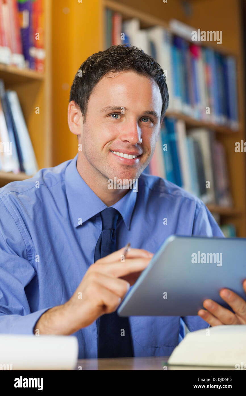 Bibliothécaire heureux sitting at desk using tablet Banque D'Images