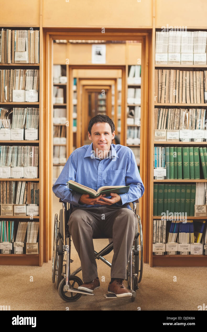 Smiling man in wheelchair holding a book Banque D'Images