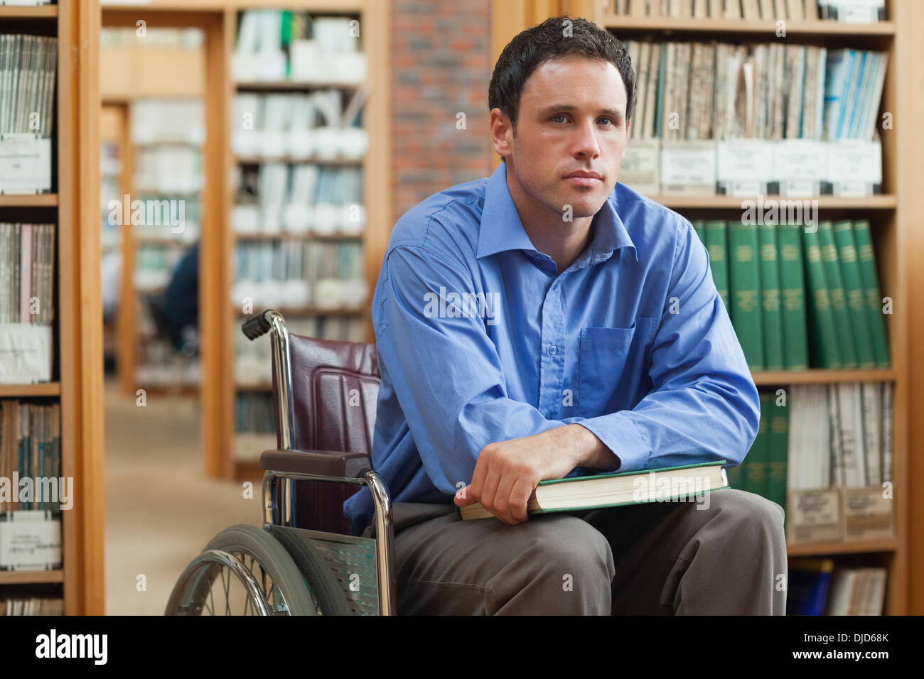 Serious man in wheelchair holding a book Banque D'Images