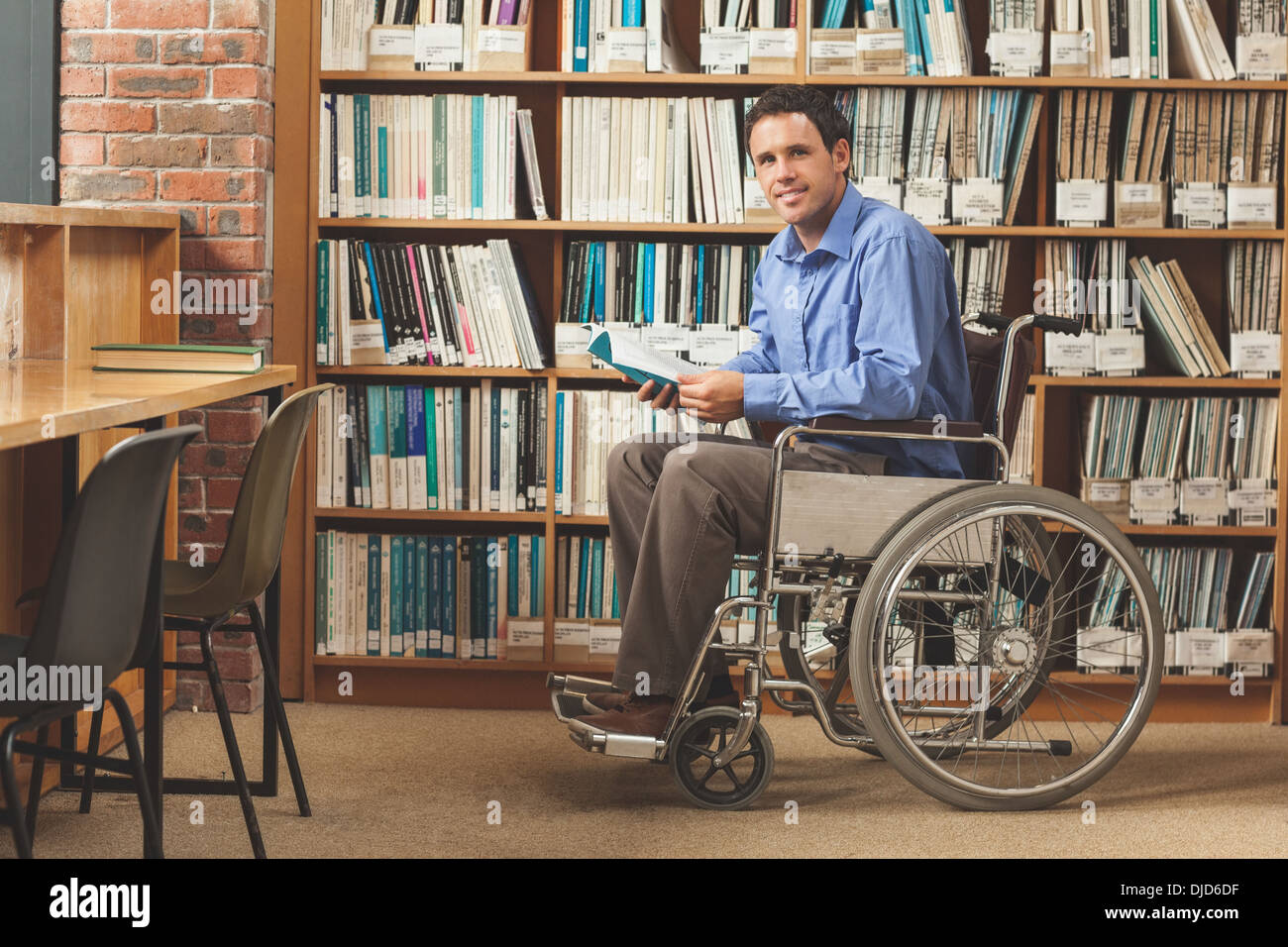 Happy man sitting in wheelchair holding a book Banque D'Images