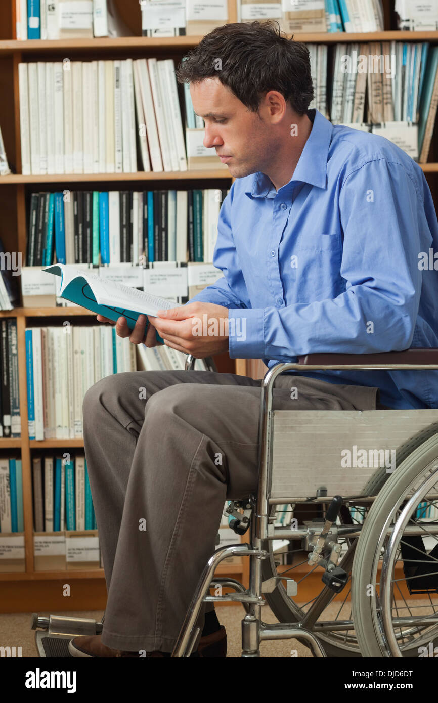 Concentrant man sitting in wheelchair reading a book Banque D'Images