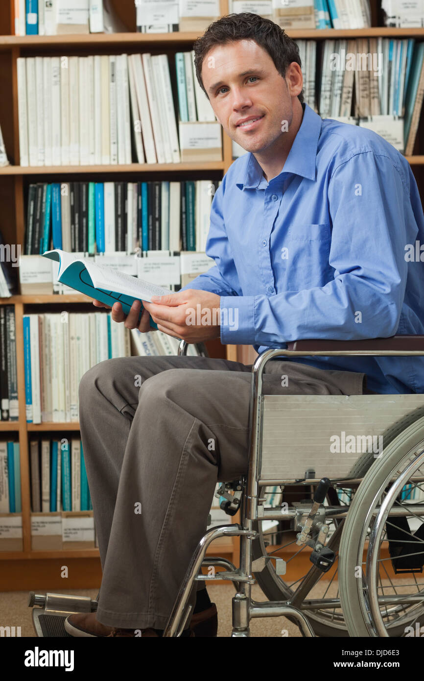 Smiling man sitting in wheelchair holding a book Banque D'Images