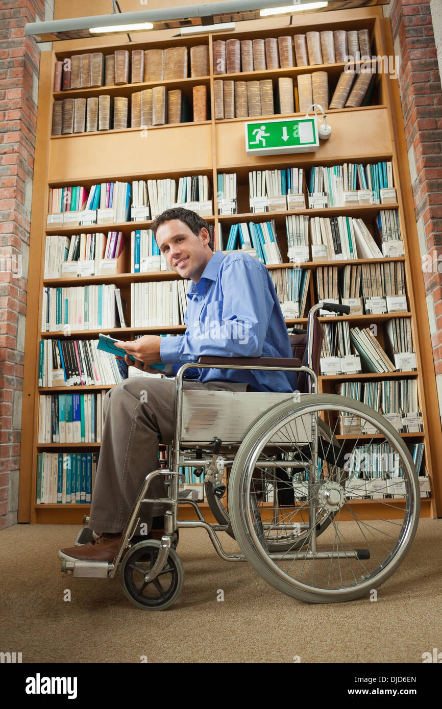 Cheerful man sitting in wheelchair holding a book Banque D'Images
