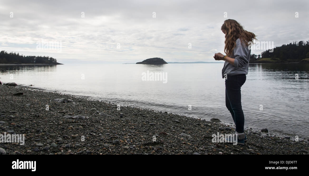 Une jeune femme se tient sur une plage rocheuse dans col Deception State Park ; Oak Harbor, Washington, United States of America Banque D'Images